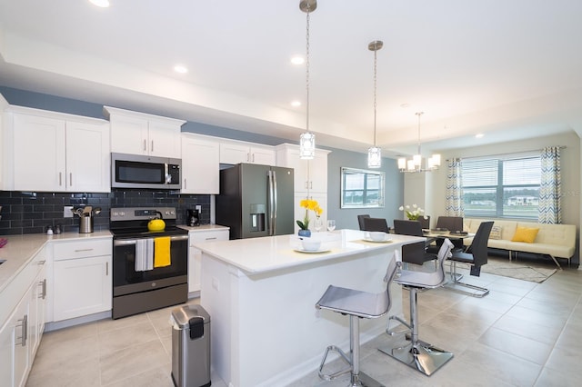 kitchen featuring decorative backsplash, stainless steel appliances, a center island, decorative light fixtures, and white cabinetry