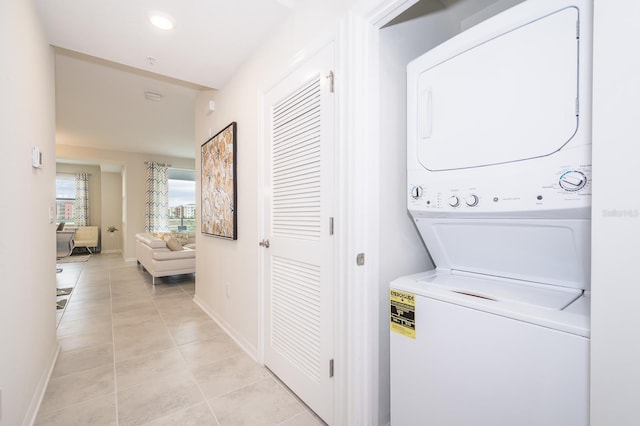 washroom with stacked washer / drying machine and light tile patterned flooring