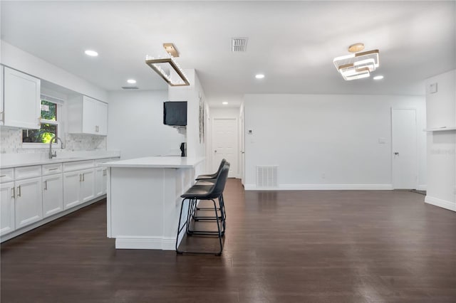 kitchen with dark wood-type flooring, a kitchen island, and white cabinets