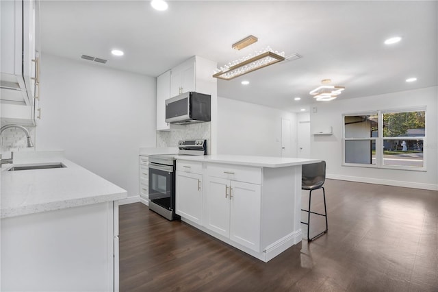 kitchen with appliances with stainless steel finishes, white cabinetry, sink, and backsplash