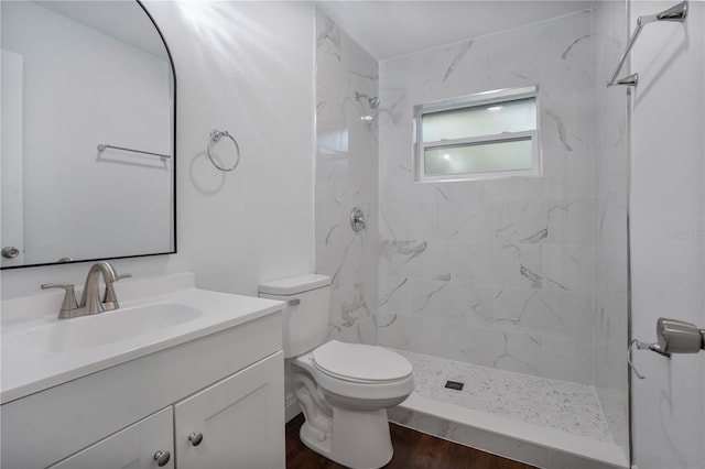 bathroom with vanity, a tile shower, hardwood / wood-style flooring, and toilet