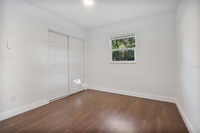 unfurnished bedroom with a closet and dark hardwood / wood-style floors