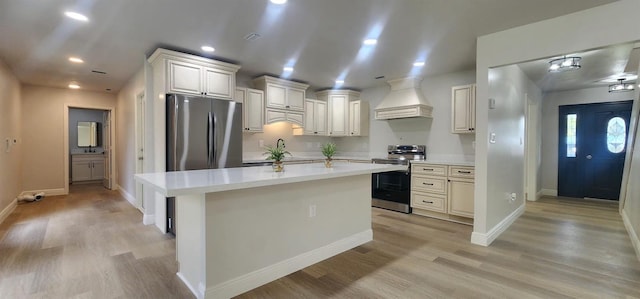 kitchen with a center island, light wood-type flooring, custom range hood, appliances with stainless steel finishes, and white cabinetry