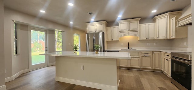 kitchen featuring sink, stainless steel appliances, light hardwood / wood-style flooring, cream cabinets, and a kitchen island