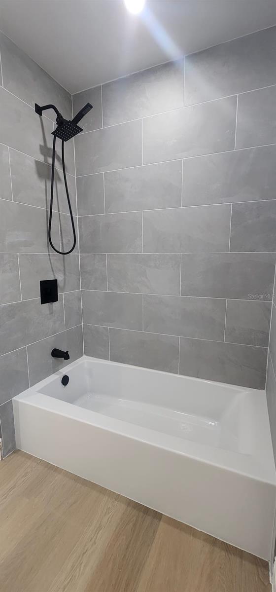 bathroom with tiled shower / bath combo and hardwood / wood-style flooring