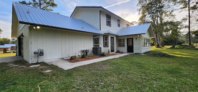 back house at dusk featuring a lawn, central AC unit, and a garage