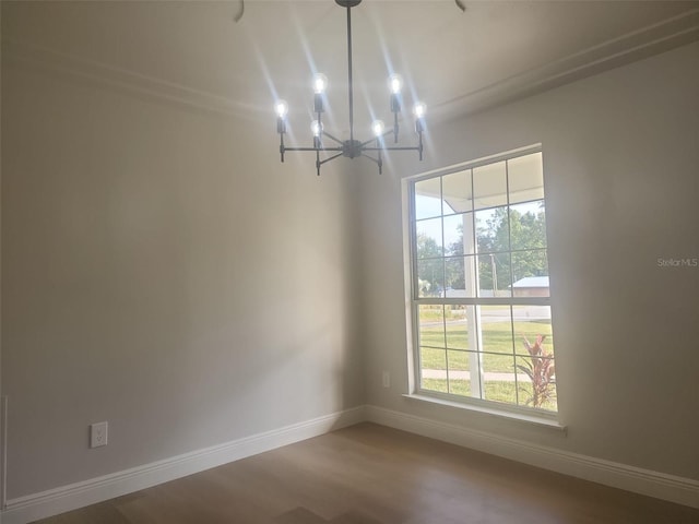 spare room featuring hardwood / wood-style flooring and a notable chandelier