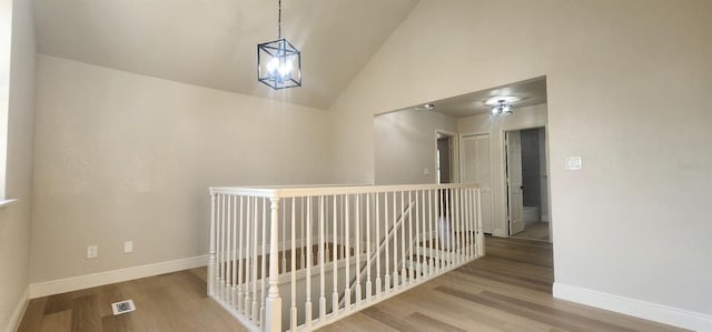 hall featuring hardwood / wood-style floors, high vaulted ceiling, and an inviting chandelier