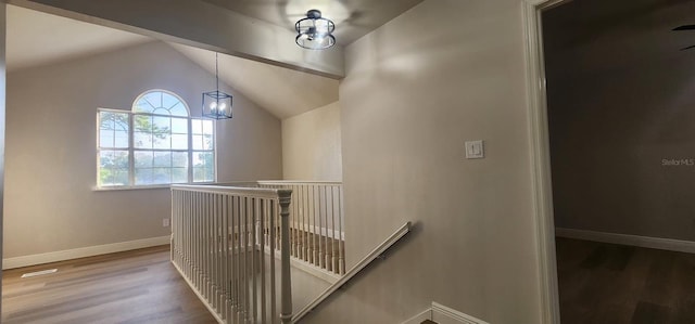 stairs featuring an inviting chandelier, wood-type flooring, and vaulted ceiling