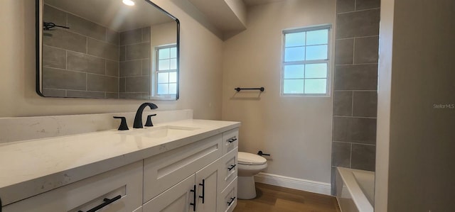 full bathroom with hardwood / wood-style floors, vanity, toilet, and tiled shower / bath