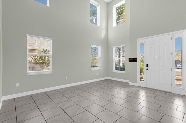 tiled entryway with a towering ceiling and a wealth of natural light