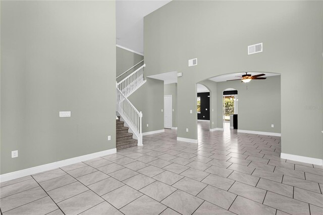 unfurnished living room featuring a high ceiling and ceiling fan