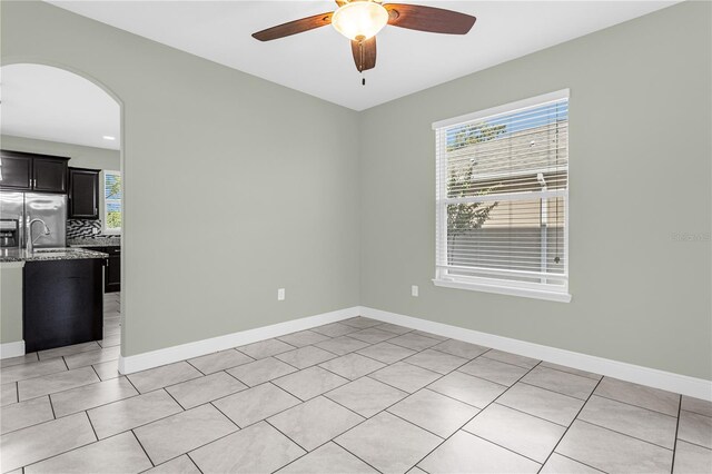 spare room featuring ceiling fan, light tile patterned flooring, sink, and a wealth of natural light