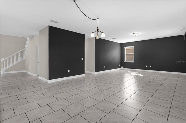 spare room with light tile patterned floors and an inviting chandelier