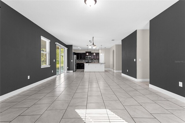 unfurnished living room featuring a chandelier and light tile patterned flooring