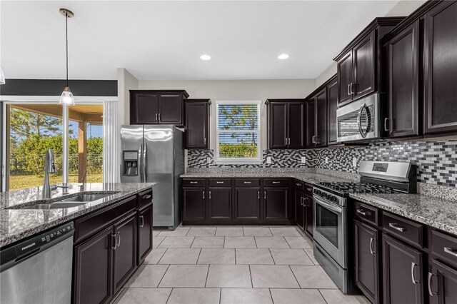 kitchen with appliances with stainless steel finishes, dark brown cabinetry, sink, and a wealth of natural light