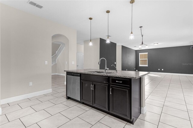 kitchen with light stone counters, a kitchen island with sink, stainless steel dishwasher, pendant lighting, and sink