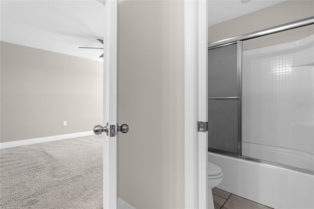 bathroom with ceiling fan, toilet, tile patterned flooring, and bath / shower combo with glass door