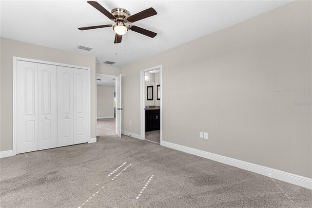 unfurnished bedroom with connected bathroom, ceiling fan, a closet, and light colored carpet