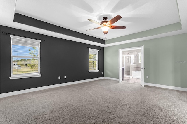 carpeted spare room featuring ceiling fan and a tray ceiling