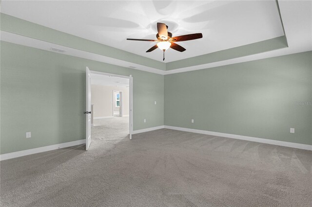 spare room with carpet floors, a raised ceiling, and ceiling fan