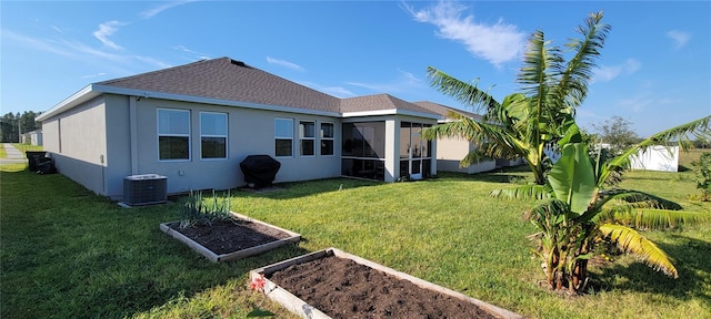 rear view of property with a sunroom, central AC, and a lawn