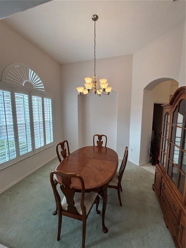 carpeted dining area with a chandelier