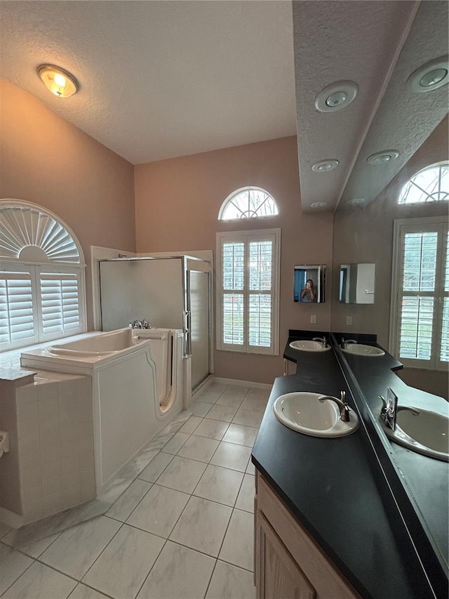 bathroom featuring tile patterned flooring, vanity, independent shower and bath, and a textured ceiling