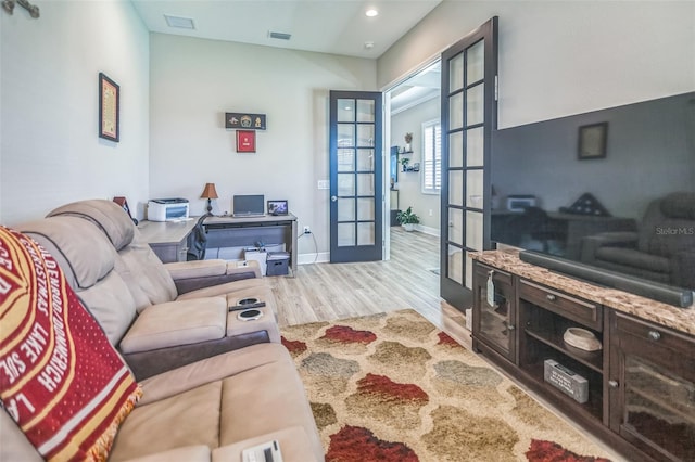 living room with french doors and light wood-type flooring