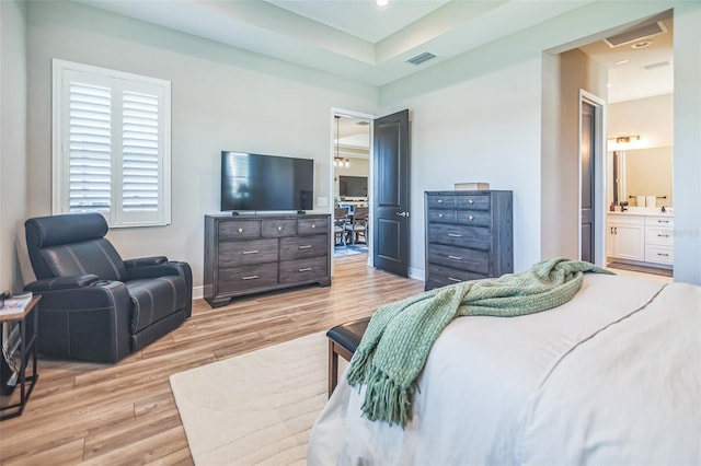 bedroom with connected bathroom and light hardwood / wood-style floors