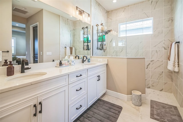 bathroom featuring vanity, a tile shower, and tile patterned flooring