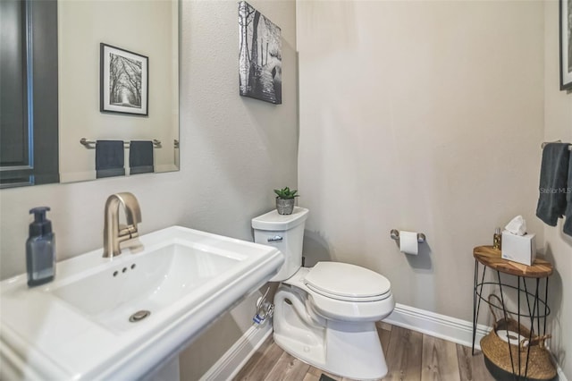 bathroom with toilet, hardwood / wood-style flooring, and sink