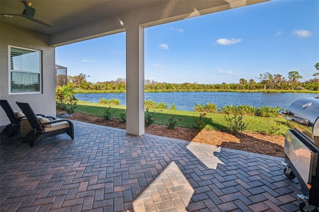 view of patio featuring grilling area, a water view, and ceiling fan