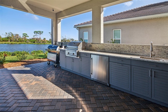 view of patio with area for grilling, sink, a water view, and grilling area