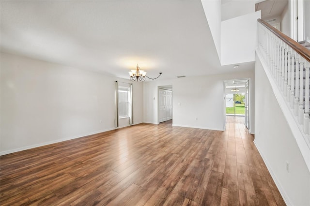 unfurnished living room with an inviting chandelier and wood-type flooring