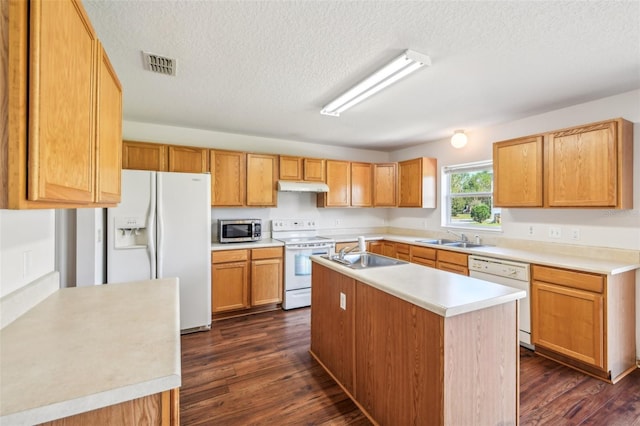 kitchen featuring dark hardwood / wood-style floors, a center island with sink, sink, a textured ceiling, and white appliances