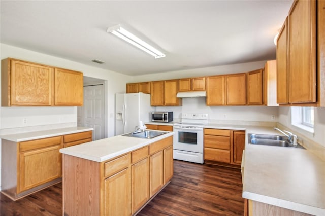 kitchen featuring white appliances, dark hardwood / wood-style floors, sink, and a center island with sink