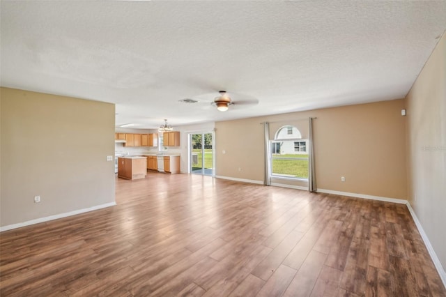 unfurnished living room with a textured ceiling, hardwood / wood-style flooring, and ceiling fan