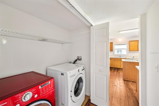 laundry room featuring washer and dryer, sink, dark wood-type flooring, and a textured ceiling