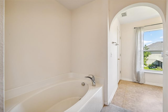 bathroom with tile patterned floors and tiled bath