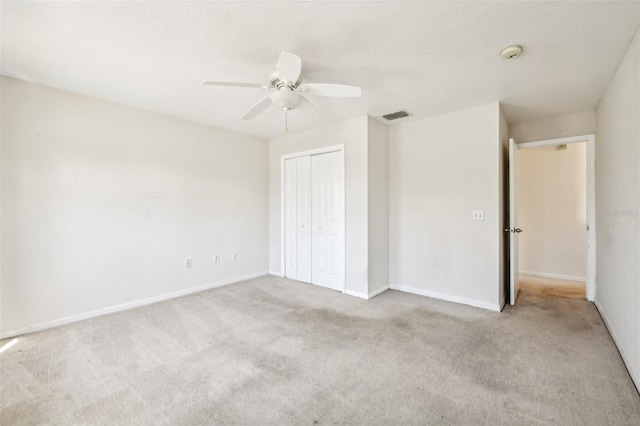 unfurnished bedroom featuring a closet, ceiling fan, light carpet, and a textured ceiling