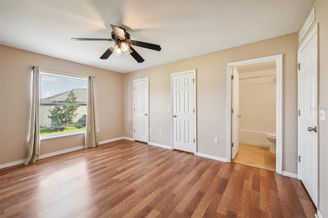 unfurnished bedroom with hardwood / wood-style floors, ensuite bathroom, a textured ceiling, and ceiling fan