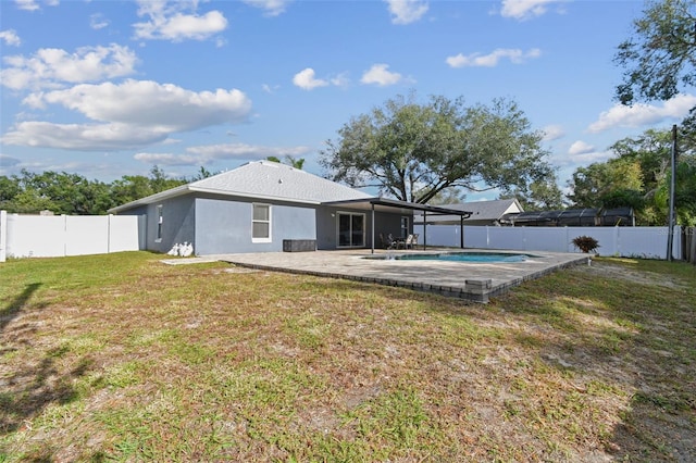 rear view of house with a fenced in pool, a yard, and a patio