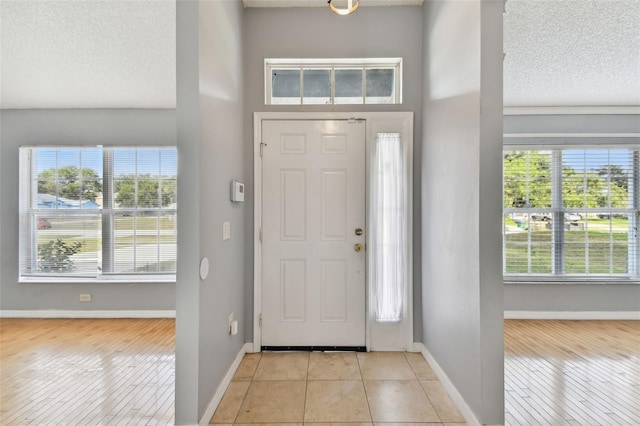 tiled entryway featuring a high ceiling, a textured ceiling, and a healthy amount of sunlight