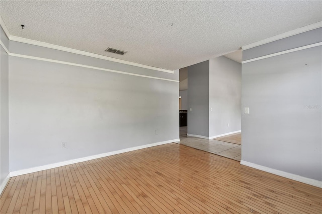 spare room featuring a textured ceiling and light hardwood / wood-style floors