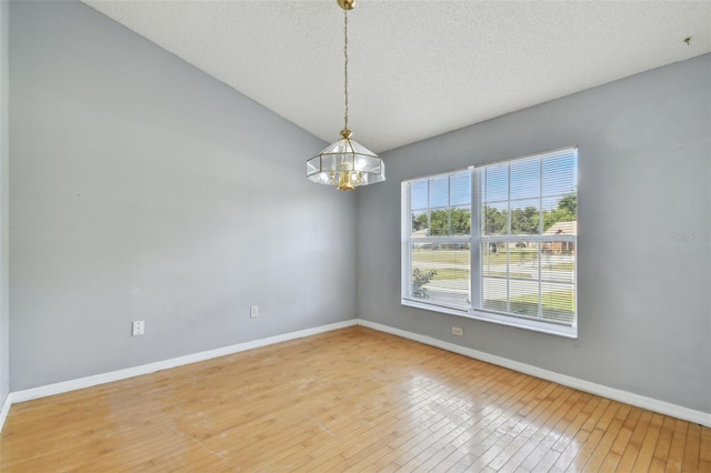 spare room with a chandelier, a textured ceiling, and hardwood / wood-style flooring