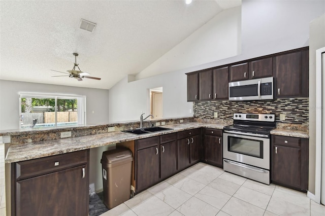 kitchen featuring dark brown cabinets, stainless steel appliances, vaulted ceiling, and sink