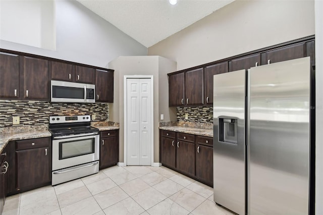 kitchen with appliances with stainless steel finishes, dark brown cabinetry, high vaulted ceiling, and light stone counters