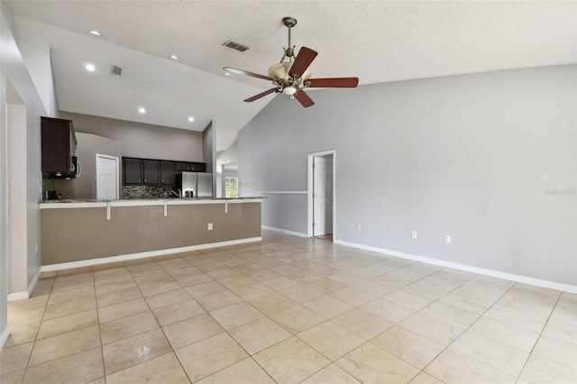 unfurnished living room featuring light tile patterned floors, a textured ceiling, high vaulted ceiling, and ceiling fan