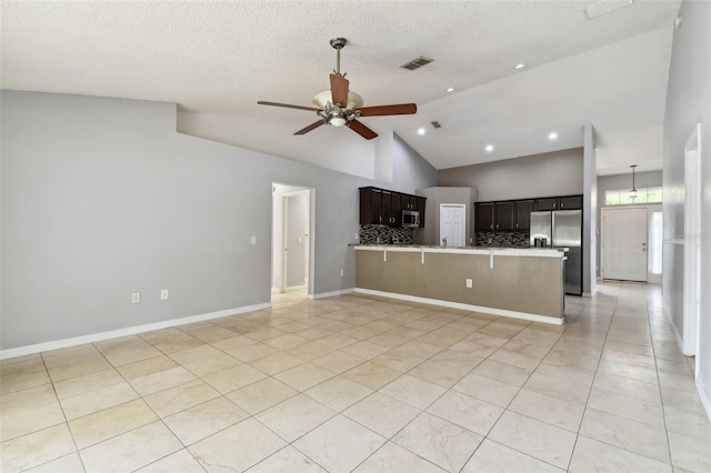 kitchen with stainless steel appliances, high vaulted ceiling, backsplash, kitchen peninsula, and a kitchen bar